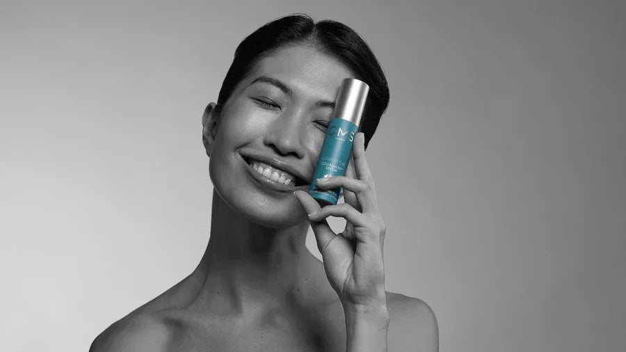 Vrouw met glimlach houdt QMS Collagen Vitality Serum vast, voor stevige, stralende huidverzorging