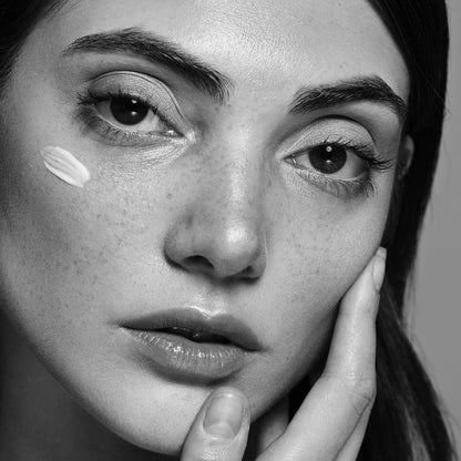 Model brengt QMS ILLUMIntense Serum aan op het gezicht